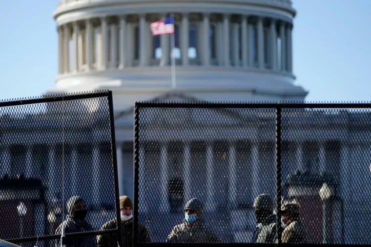 With the U.S. Capitol in the background, members of the National Guard stand behind newly placed fencing around the Capitol grounds the day after violent protesters loyal to President Donald Trump stormed the U.S. Congress in Washington, Thursday, Jan. 7, 2021.
