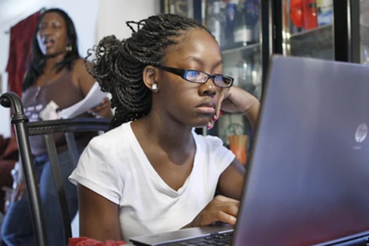 Naveda Walker, 14, does work for Agora Cyber Charter School on a home computer in Overbrook as mother Wanda watches. (Elizabeth Robertson / Staff Photographer)