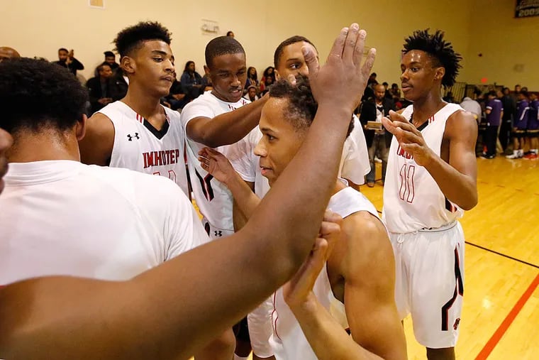 Imhotep's Daron Russell (center) is congratulated by teammates after the he went over 1,000 points in his career.