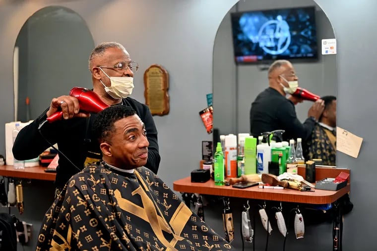 Doug Walker styles Aaron Lane's hair, as he has for the last two decades, at his shop, Sharp Cuts Above, in North Philadelphia.