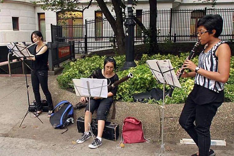 Protest song: Julia Masterman High School seniors (from left) Gloria Yuen, Tracy Nguyen and Doreen McNeill play for passers-by yesterday in the City Hall courtyard. The students showcased their talents as a demonstration against proposed cuts to the school district's arts and music programs. (Yong Kim/Staff)