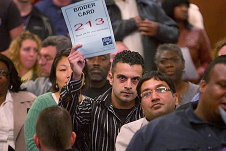Rahil Razo holds up his bid sheet while making the winning offer on a property during Wednesday's PHA auction. (Ed Hille / Staff Photographer)
