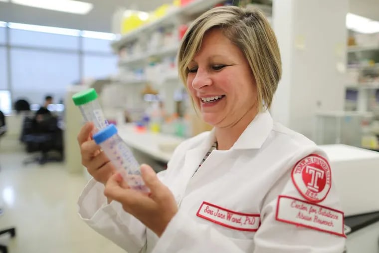 Sara Jane Ward holds two vials of CBD in her hands in her lab at Temple University in 2018. She is now studying a modified version of CBD to treat chemotherapy-induced pain.