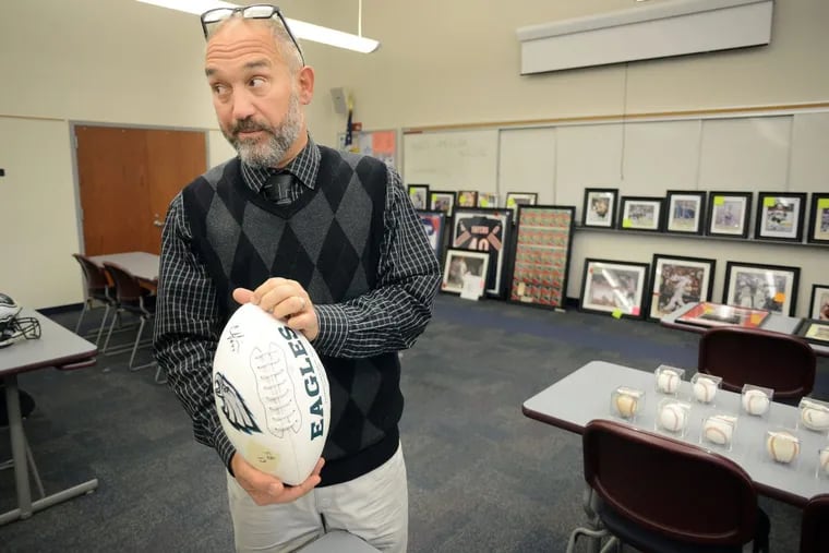 Auctioneer Alfred Finocchiaro holds up a football signed by a Philadelphia Eagles player during the preview of an online auction of sports memorabilia, most of which came from Mark Begley, a Cherry Hill man arrested for mortgage fraud two years ago.