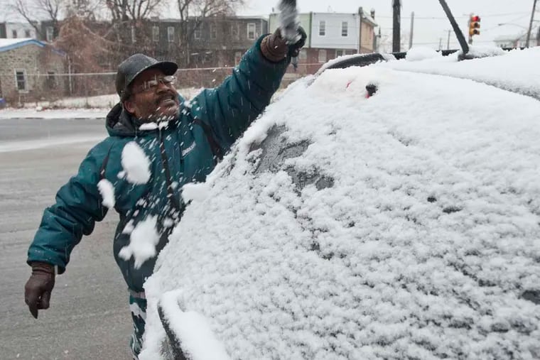 Nathan Rollins of West Oak Lane flicks snow from his car during the first snowfall of the season on November 26, 2014. ( RON TARVER / Staff Photographer )