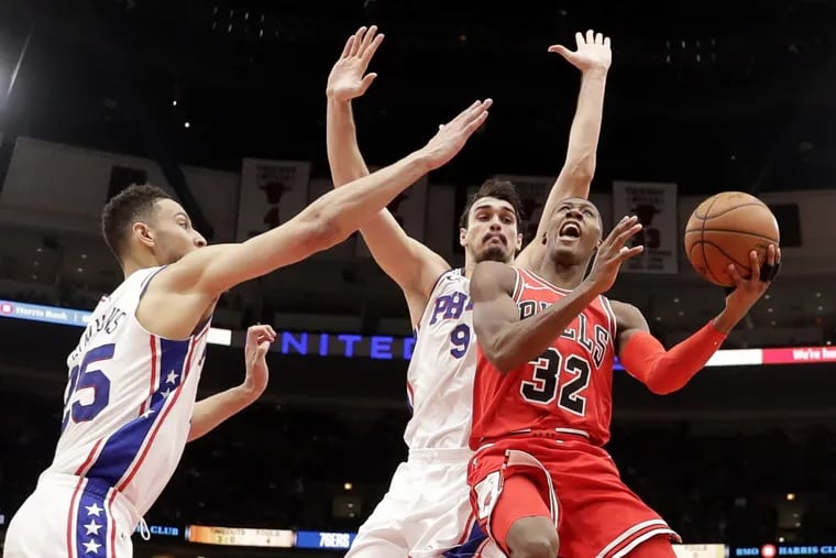 The Bulls' Kris Dunn (32) shooting against Sixers Ben Simmons (25) and Dario Saric during the teams’ December meeting.
