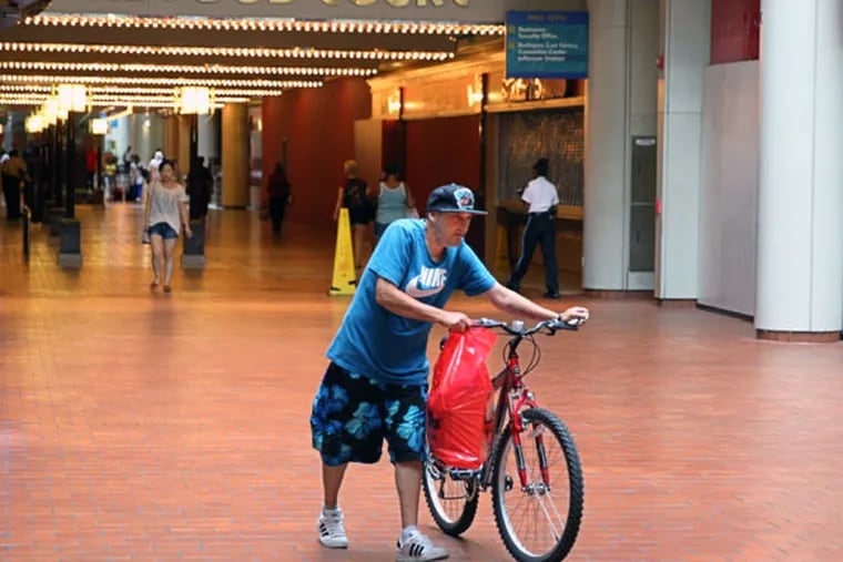 A pedestrian walks his bike through the Gallery mall. (Michael Bryant/Staff Photographer)