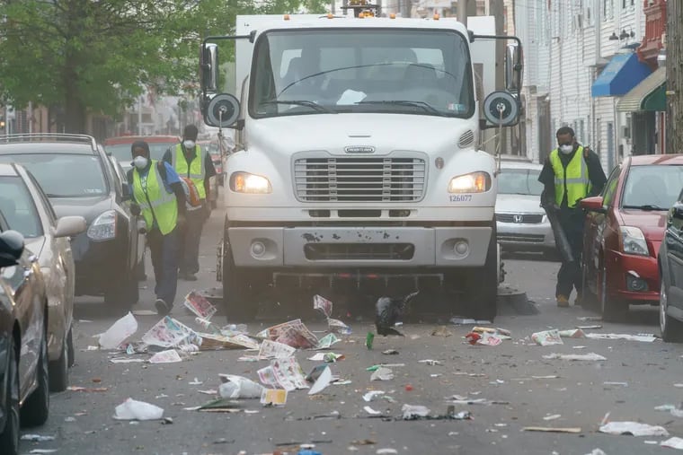Street Sweeping crews blow trash into the street to be picked up by a truck, on South 7th street, in Philadelphia, May 2, 2019.