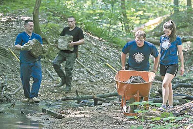 Volunteers (from left) Jason Crain, Charlie Sedor, Matt Williams, and Emily Vernamonti haul chunks of concrete from a stream. “You never know what you’re going to find,” Sedor says. (AKIRA SUWA / Staff Photographer)