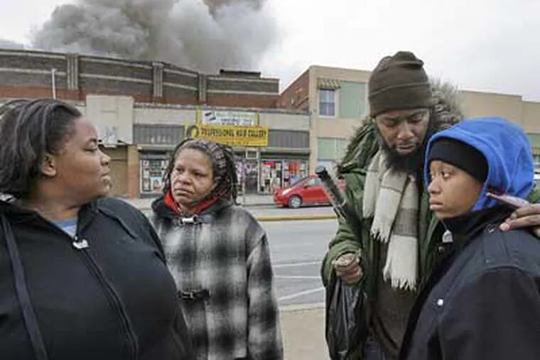 Residents of Grange Manor Apartments Theresa Fife (left) and her sister Cathy Lyles (right) are consoled by their mom Nana El (2nd from Left) and their brother Gregory Young near the fire scene on Broad Street on Saturday.  (Akira Suwa / Staff Photographer)