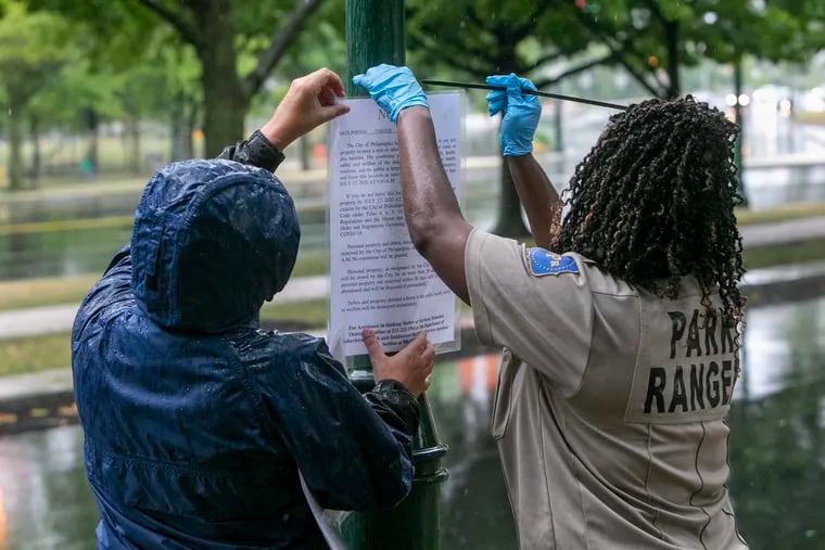 Park Rangers post signs Friday morning ordering the homeless encampment on Benjamin Franklin Parkway to be vacated by July 17.