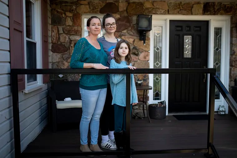Mandy Crozier 40, curriculum  coordinator at Kinder Academy, left, and her daughters, Jacey Crozier, 21, center, and Savannah Crozier, 10, right, in front of their home. Both Mandy and Jacey were laid off from Kinder after the COVID-19 related shut-down. Mandy has been reaching out to teachers and students while at home.