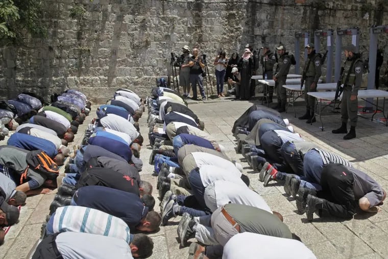 Israeli border police officers stand guard as Muslim men pray outside the Al Aqsa Mosque compound in Jerusalem on Sunday.
