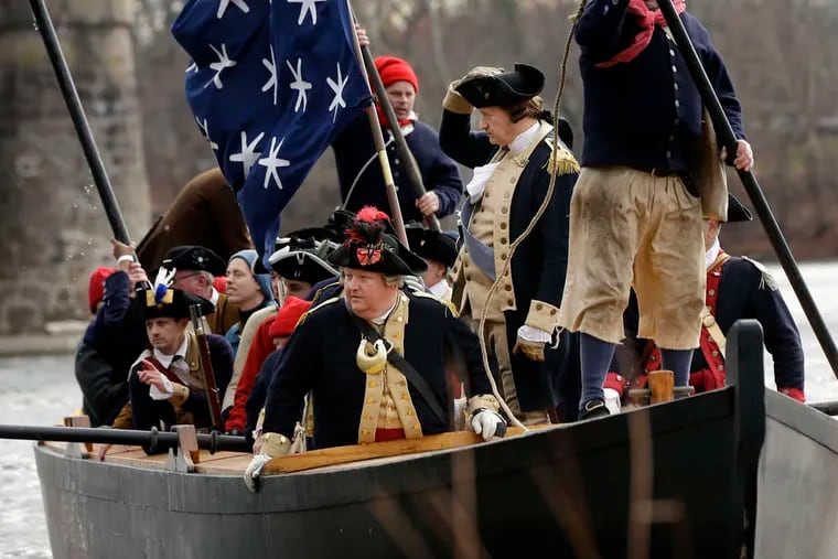 John Godzieba (holding his hat) plays Gen. George Washington crossing the Delaware between Washington Crossing and Titusville, N.J., joined by fellow reenactors playing his troops.