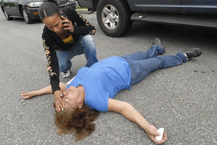 Overwhelmed by grief, Jose Feliciano’s grandmother Luisa Diaz collapses in the street in Camden’s Baldwin Run neighborhood. Feliciano’s sister Crystal Mendez tried to help her. (April Saul / Staff Photographer)