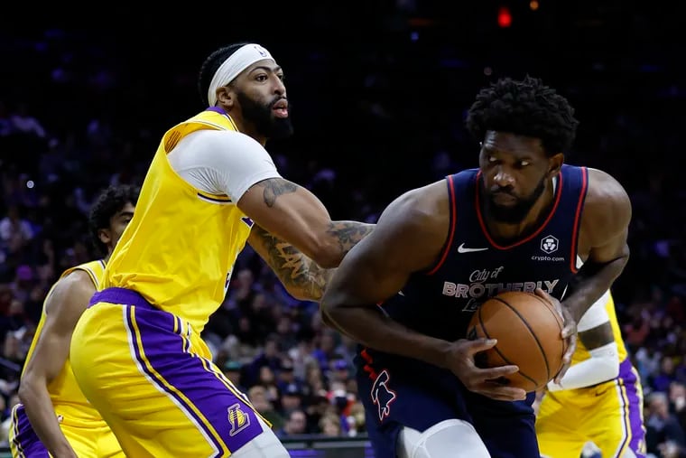 Sixers center Joel Embiid holds the basketball defended by Los Angeles Lakers forward Anthony Davis on Monday, November 27, 2023 in Philadelphia.