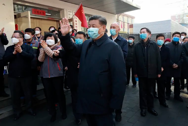 Chinese President Xi Jinping, centre, wearing a protective face mask waves as he inspects the novel coronavirus pneumonia prevention and control work at a neighbourhoods in Beijing, Monday, Feb. 10, 2020. China reported a rise in new virus cases on Monday, possibly denting optimism that its disease control measures like isolating major cities might be working, while Japan reported dozens of new cases aboard a quarantined cruise ship.
