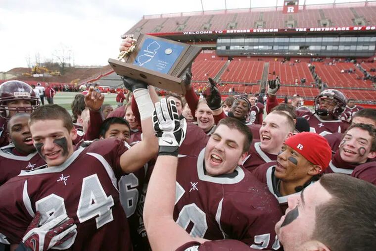 Joe Innaurato (left), Mike Howley (center) and their Holy Cross teammates make merry with the state championship trophy.