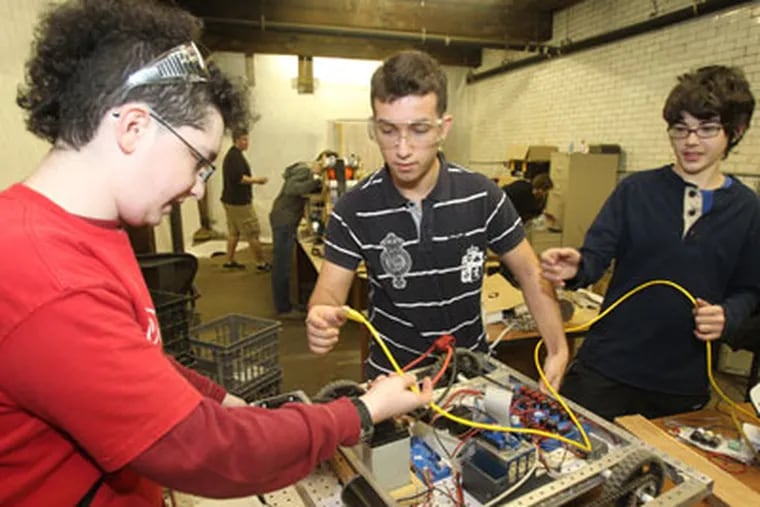 Massive budget cuts in the Philadelphia School District that ended robotics clubs in the fall at 15 district schools.  The Masterman Atomic Robotics 4-H club created a regional team and opened up membership to students across the district.  L-R:  Emmett Neyman, Mikelanxhelo Novruzaj, and Max Fine, all Masterman students, work on the robots base.  ( Charles Fox / Staff Photographer )  INEROBOTICS30P, 1/25/2012,  HIGH SCHOOL ROBOTICS CLUBS, 3851 ARREN ST., PHILA., PA.