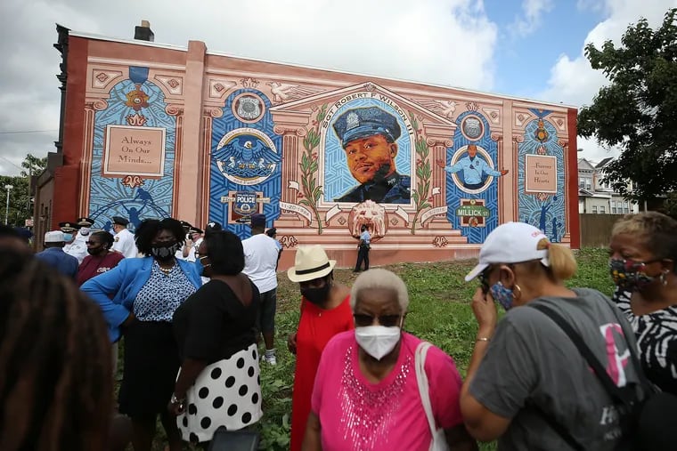 A group gathers in front of a mural of Philadelphia Police Sgt. Robert Wilson III in Philadelphia, Pa. on Sept. 1, 2020. The mural, on Baltimore Avenue near 60th Street, was vandalized early Sunday morning.