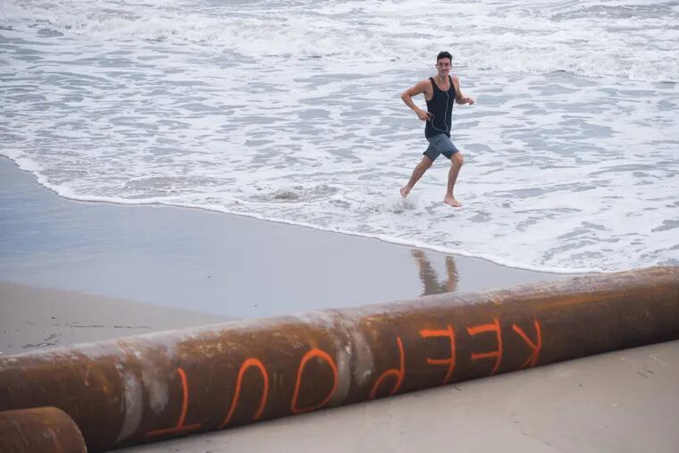 A runnier makes his way toward dredging pipes with “Keep Out” painted on them in Margate.