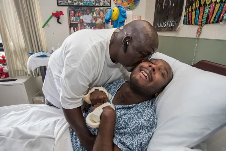John Snowden, kisses his youngest son, Khalif. Khalif, 33, was left in a vegetative state after cops tased him in the neck in 2011. John visits Khalif every day at Genesis HealthcareÕs Hopkins Center waiting for his son to come back to him. He is shown on June 22, 2018. CHARLES FOX / Staff Photographer