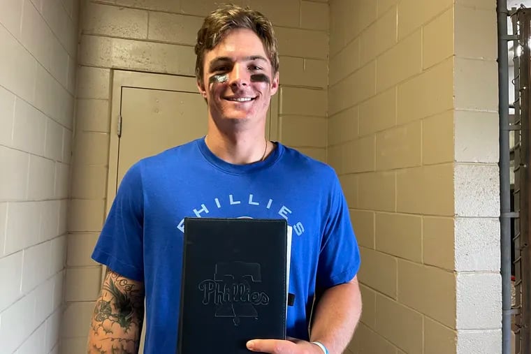 Phillies center fielder Mickey Moniak poses with the black journal he's used this offseason and spring training
