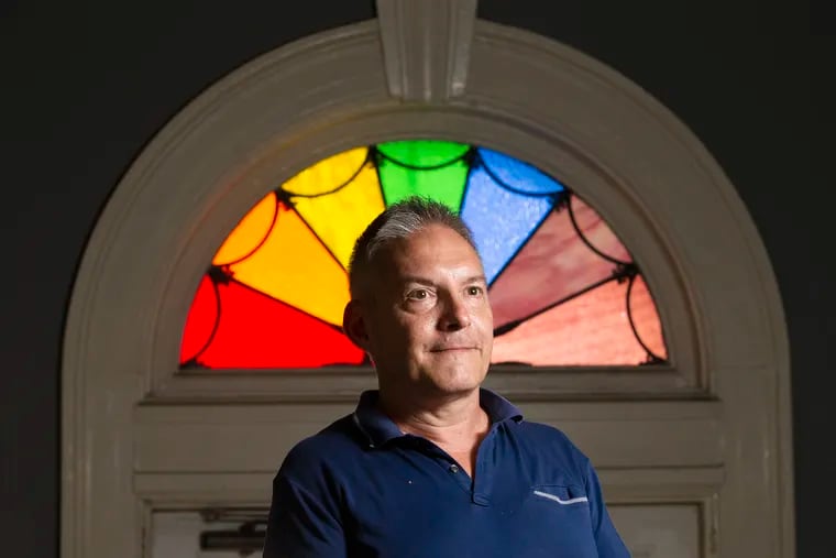 The William Way Center is sponsoring Remembrance, an ongoing experience-oriented AIDs/HIV memorial. In May, there was a play.  June 25, there will be a memorial service followed by a procession for the people who died during the AIDS crisis, Chris Bartlett, executive director of the center, is shown by the Rainbow Window by Henri David on June 16, 2022. The window encourages all to come and go with a smile.