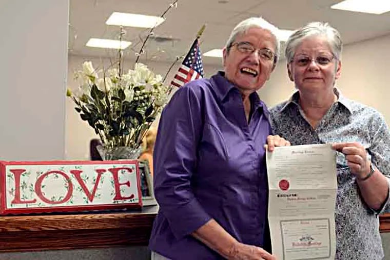 A day after the Gorbett administration asked Commonwealth Court to issue an injunction to stop Montgomery County from issuing any more licenses or accepting marriage certificates from gay and lesbian couples, the Register of Wills Office continued to issue marriage licenses to same-sex couples. Peg Welch (right) and Delma Welch, pose with their newly-issued marriage license in the Norristown office July 31, 2013. Together for 23 years, the Welches drove in from York for the licence. They were married in Toronto in 2004 and have been waiting to get married in Pennsylvania. Their wedding was to be later in the evening in York. ( TOM GRALISH / Staff Photographer )