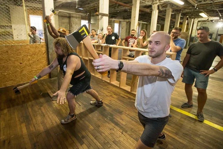 At Urban Axes in East Kensington, Brian Langan (center) gives ax-throwing lessons before an evening of fun.