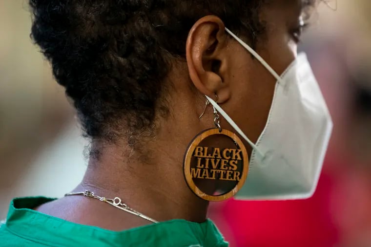 An attendee wears earrings that read "Black Lives Matter" during "Rise Up for Reparations," a multi-faith gathering at the Friends Center in Old City in June 2022.