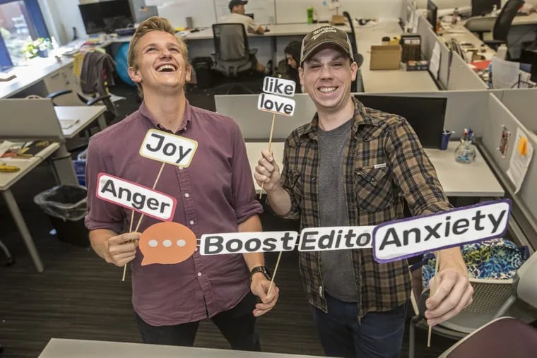 Ethan Bresnahan (left) and Jeff Nowak, two of the cofounders of Boost Linguistics, hold up visual aids representing the emotions their software aims to help those who write marketing content evoke.