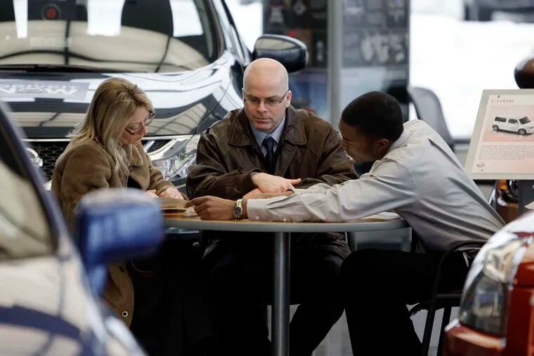 A salesman and two customers at a Nissan dealership. Low gasoline prices are a boon to consumers. But for low-income households, things are still a stretch.