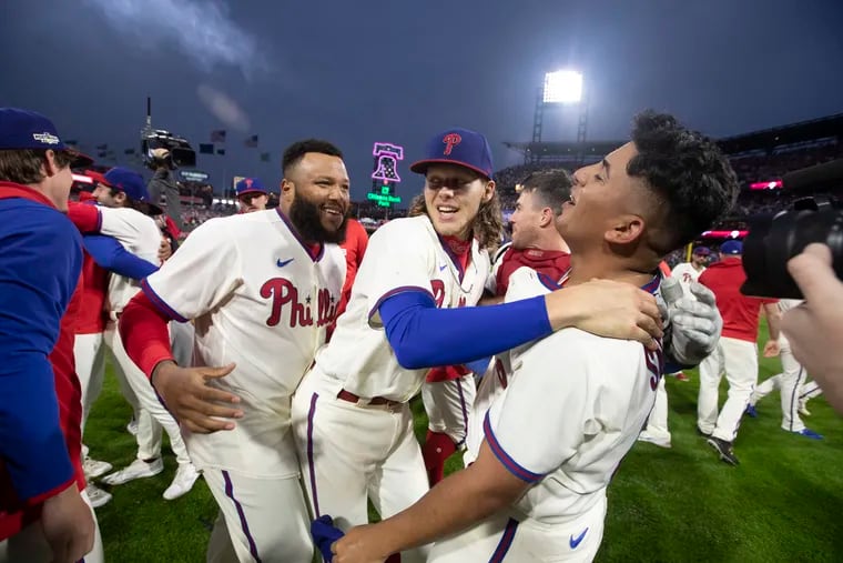 José Alvarado, left, Alec Bohm and Ranger Suárez celebrate their victory over the Padres in Game 5 of the NLCS on Sunday.
