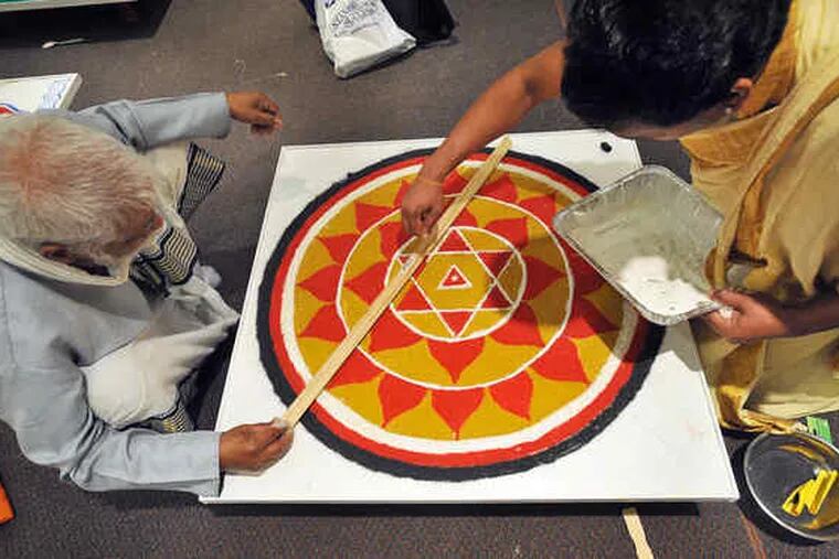 In the cultural center of the new Bharatiya Temple in Chalfont, priests from across the country and India create a yantra of colored rice, readying for Prana Pratishtha Mahotsava ceremony.