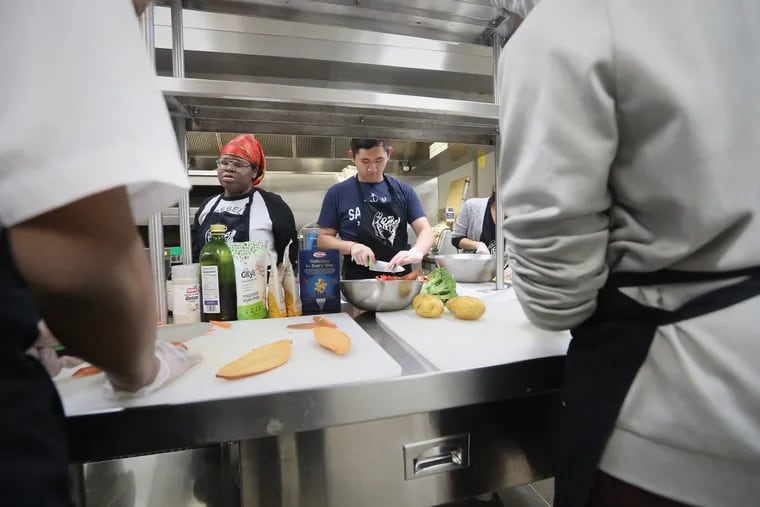 Benjamin Seing of Rebel Ventures chops vegetables at the Dorrance H. Hamilton Center for Culinary Enterprise. Rebel Ventures, a youth-led organization, has sold over 1 million healthy breakfast cakes and aims to open a convenience store next year.