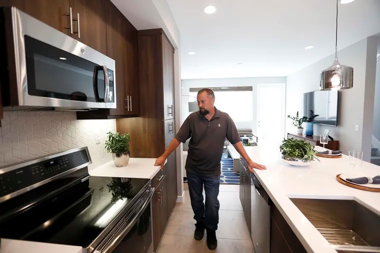 Construction manager Chris Smith shows off an induction cooktop at an all-electric, solar-powered townhouse development built by City Ventures in Bellflower, Calif., in 2019.