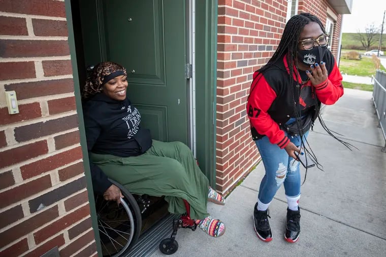 Corynna Martin (left) and Victoria Wylie laugh after Wylie delivered a prepared turkey dinner to Martin’s Strawberry Mansion home on Wednesday. Wylie is a facilitator of the paralyzed gunshot survivor support group.