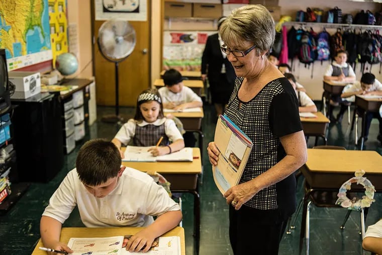 Patricia Lafferty, a third-grade teacher at St. Anthony of Padua in South Philadelphia, checks students' work on a cursive handwriting lesson. ( Matthew Hall / The Daily News )