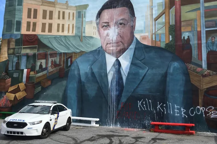A police car is parked in front of the Frank Rizzo mural after it was vandalized in South Philadelphia.