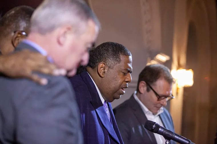 The Rev. Mark Hatcher, center, says a prayer at a 2018 press conference about the Met Philadelphia, the venue where Holy Ghost Headquarters Revivalist Center also worships. Three people, including a former member of Holy Ghost, have accused Hatcher of sexually abusing them when they were minors, according to prosecutors in Montgomery County.