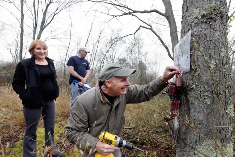 Devon Rutherford and Greg Preston watch as James Rutherford Sr. puts up a new photo of James "Jimmy" Rutherford Jr. at his son's favorite spot in the Wharton State Forest. The budding biologist felt at home there.