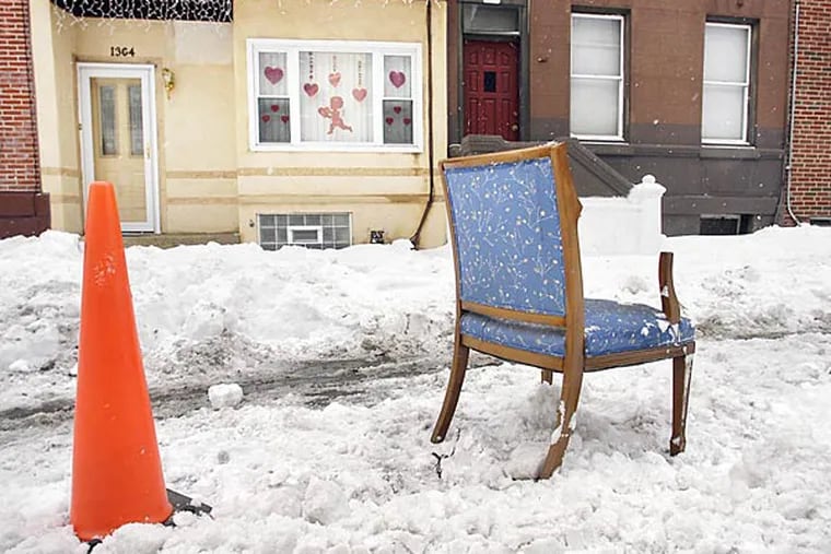 Parking spots on Ellsworth Street between 13th and Broad are  "reserved" with a pylon and a chair on Wednesday, Feb. 18, 2014. (Eric Mencher/Staff)