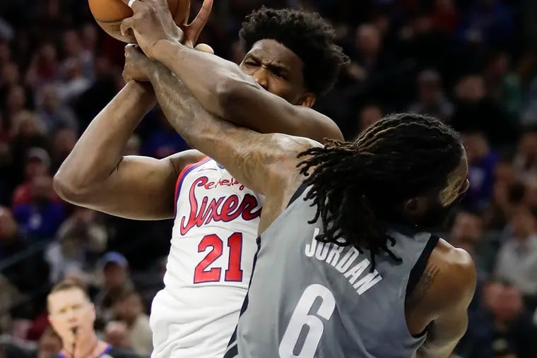 Sixers center Joel Embiid tries to control the basketball against Brooklyn Nets center DeAndre Jordan on Thursday.