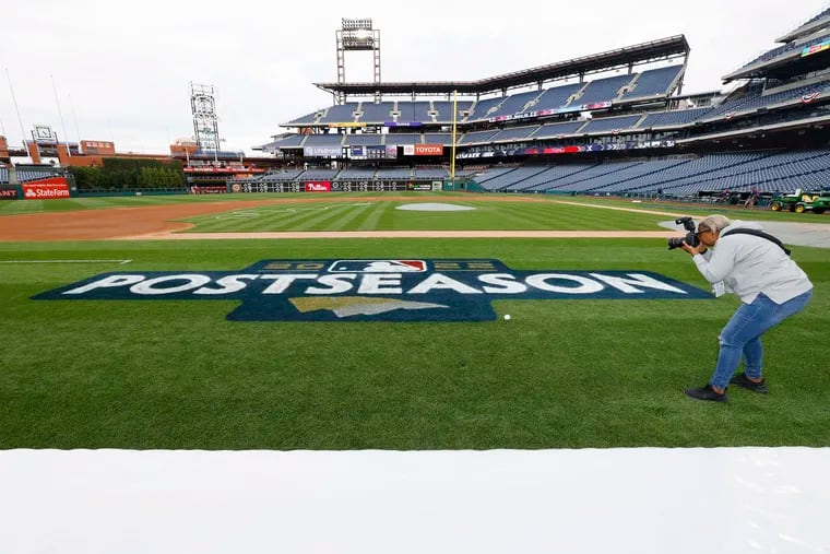 Phillies team photographer Chandra Jones makes a photograph of the MLB postseason logo that the grounds crew had just painted on the playing field at Citizens Bank Park. The 11-year-wait is about to end.