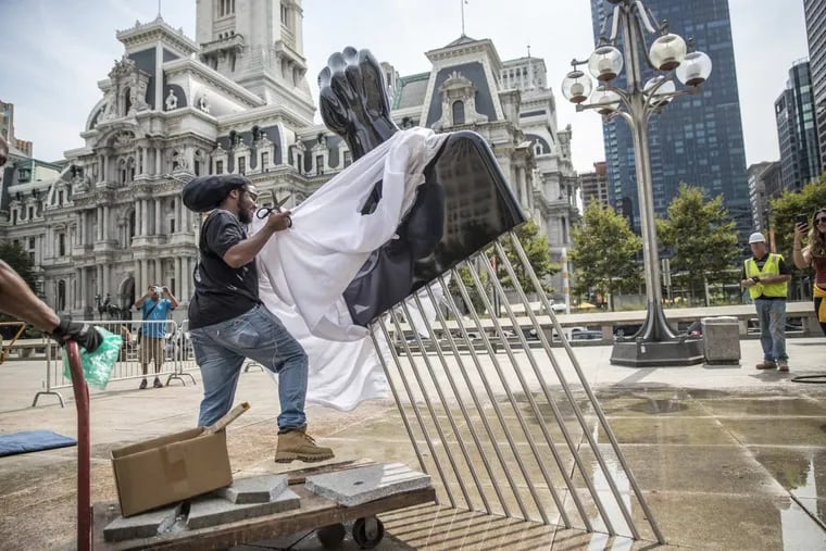 Will Sylvester uncovered the Hank Willis Thomas sculpture “All Power to All People” at the Thomas Paine Plaza across from Philadelphia City Hall as part of the 2017 Mural Arts Monument Lab project.