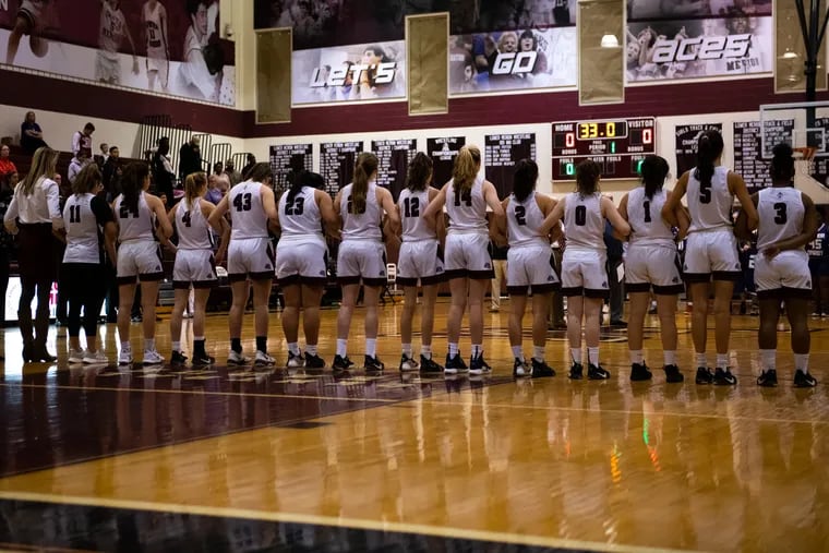 The Lower Merion girls' basketball team links arms before a 33-second moment of silence for Kobe Bryant before their game against Upper Darby.