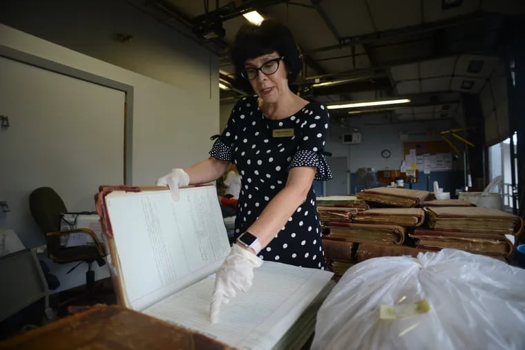 Robin Robinson, Bucks County's recorder of deeds, looks through some old county deed books at the county storage facility. Robinson is initiating an effort to preserve hundreds of deed books, some of which date back to William Penn.