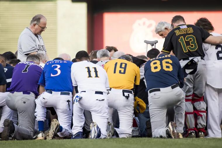 Patrick Conroy, Chaplain of the House of Representatives, left, leads both teams in a moment of prayer before the start of the annual Congressional Baseball Game at Nationals Park.