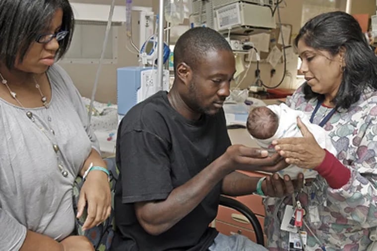 Heena Patel, Clinical Coordinator at NICU, hands Quinzel Kane Jr. very carefully to the father, Quinzel Kane Sr., while the mother, Charmaine Harris (left) watches. (Akira Suwa / Staff Photographer)